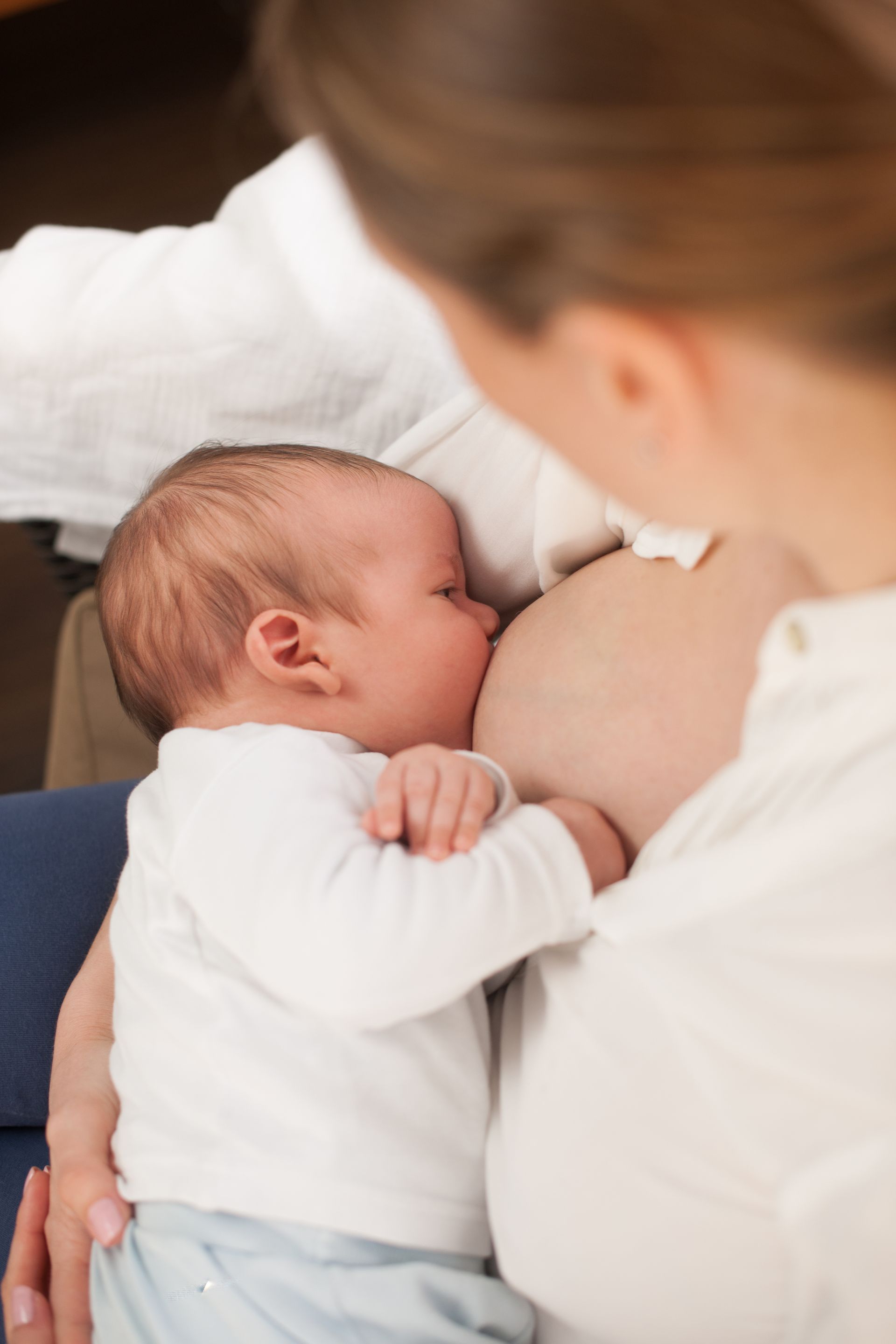 A woman is breastfeeding her baby in her arms.