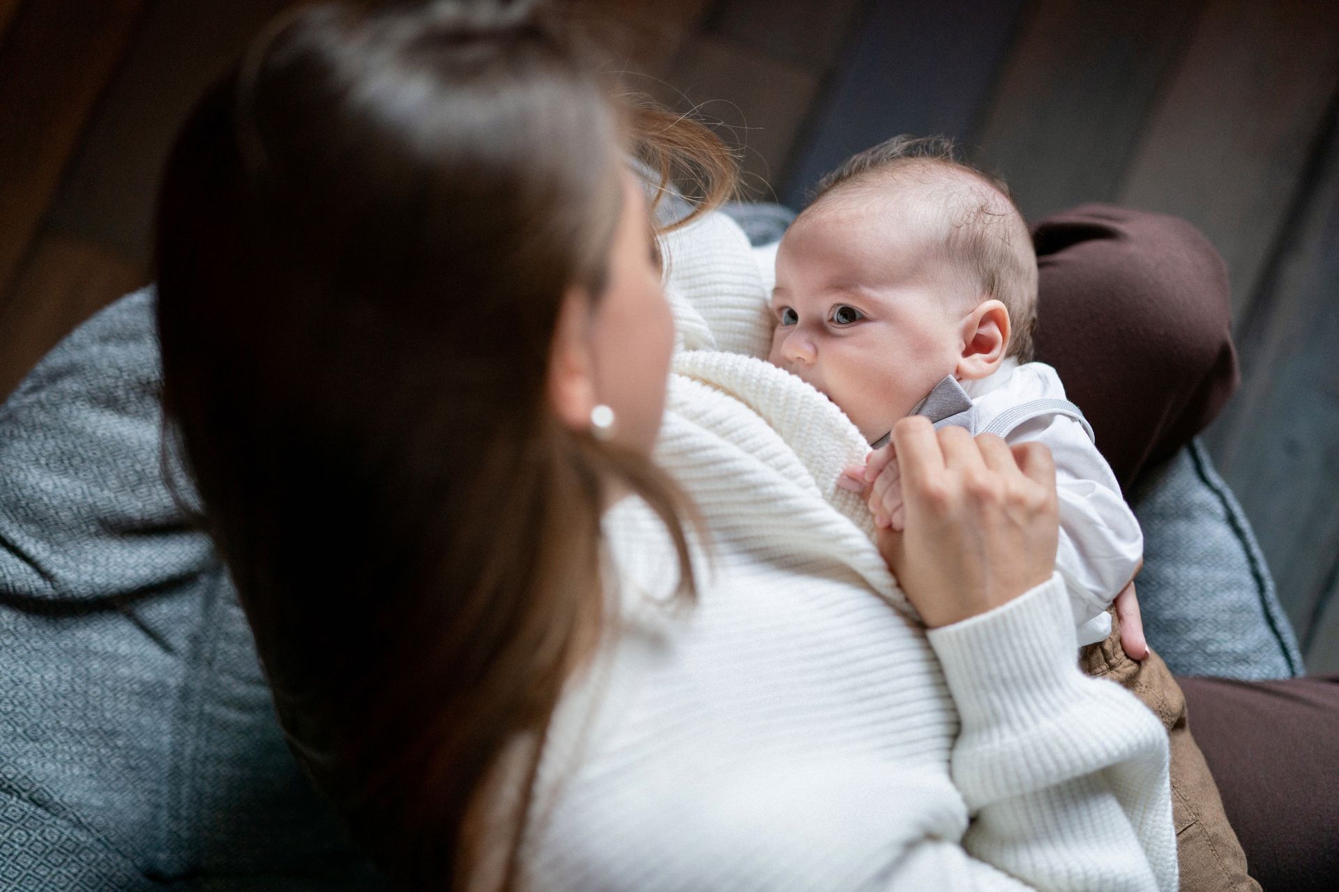 A woman is breastfeeding her baby while sitting on a couch.