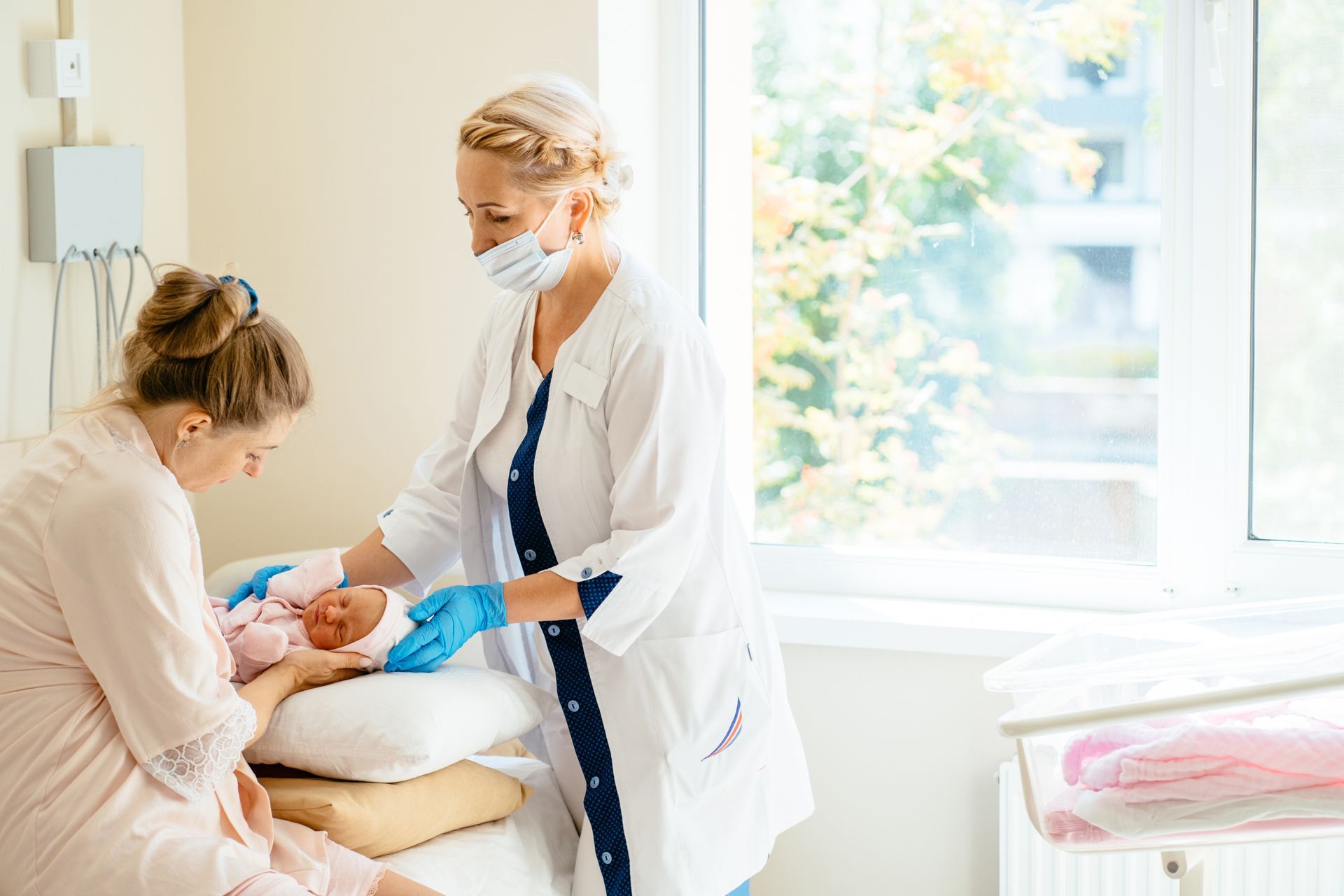 A nurse is holding a baby while a pregnant woman looks on.