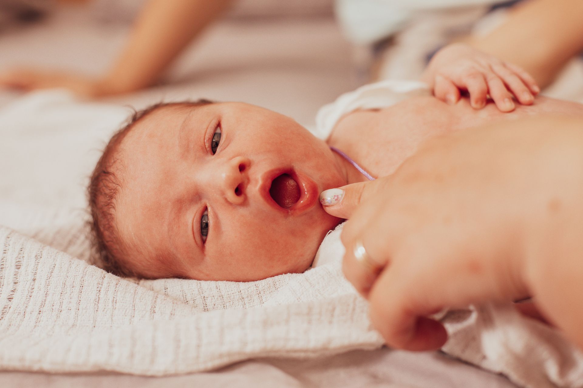 A newborn baby is laying on a blanket on a bed.