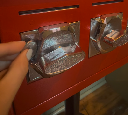 Hand tightening a silver latch on a red metal cabinet with another latch beside it