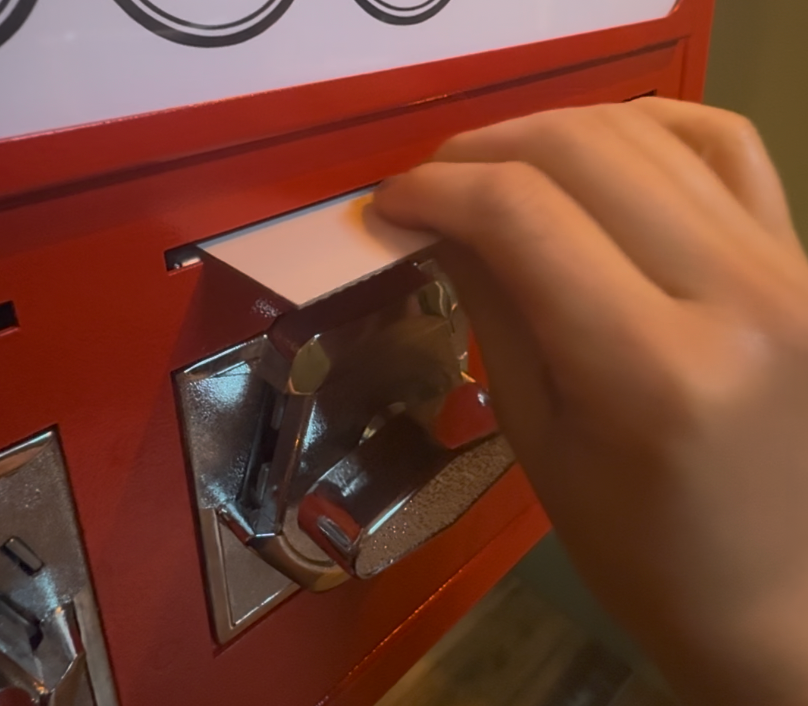 Hand turning a chrome knob on a red vending machine