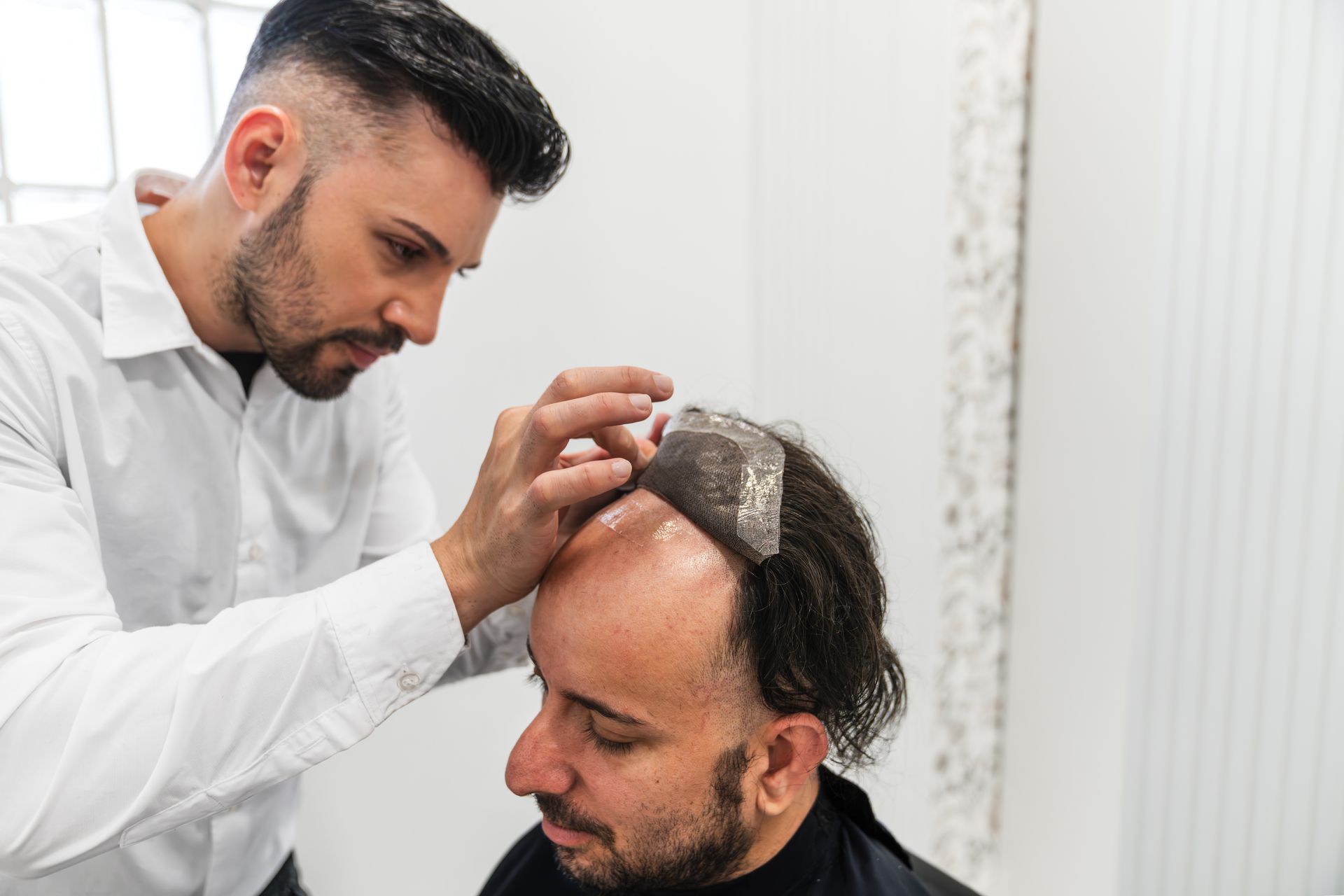 Non-surgical hair replacement being applied to cover thinning hair