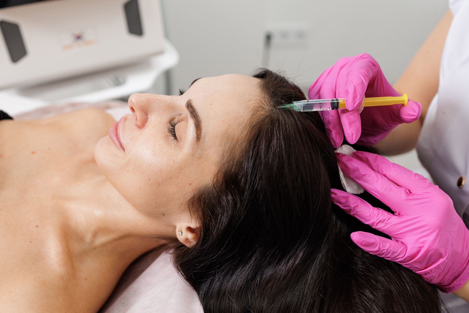 A woman receives an injection on the scalp for hair loss treatment in a clinic. A woman receives an injection on the scalp for hair loss treatment in a clinic.