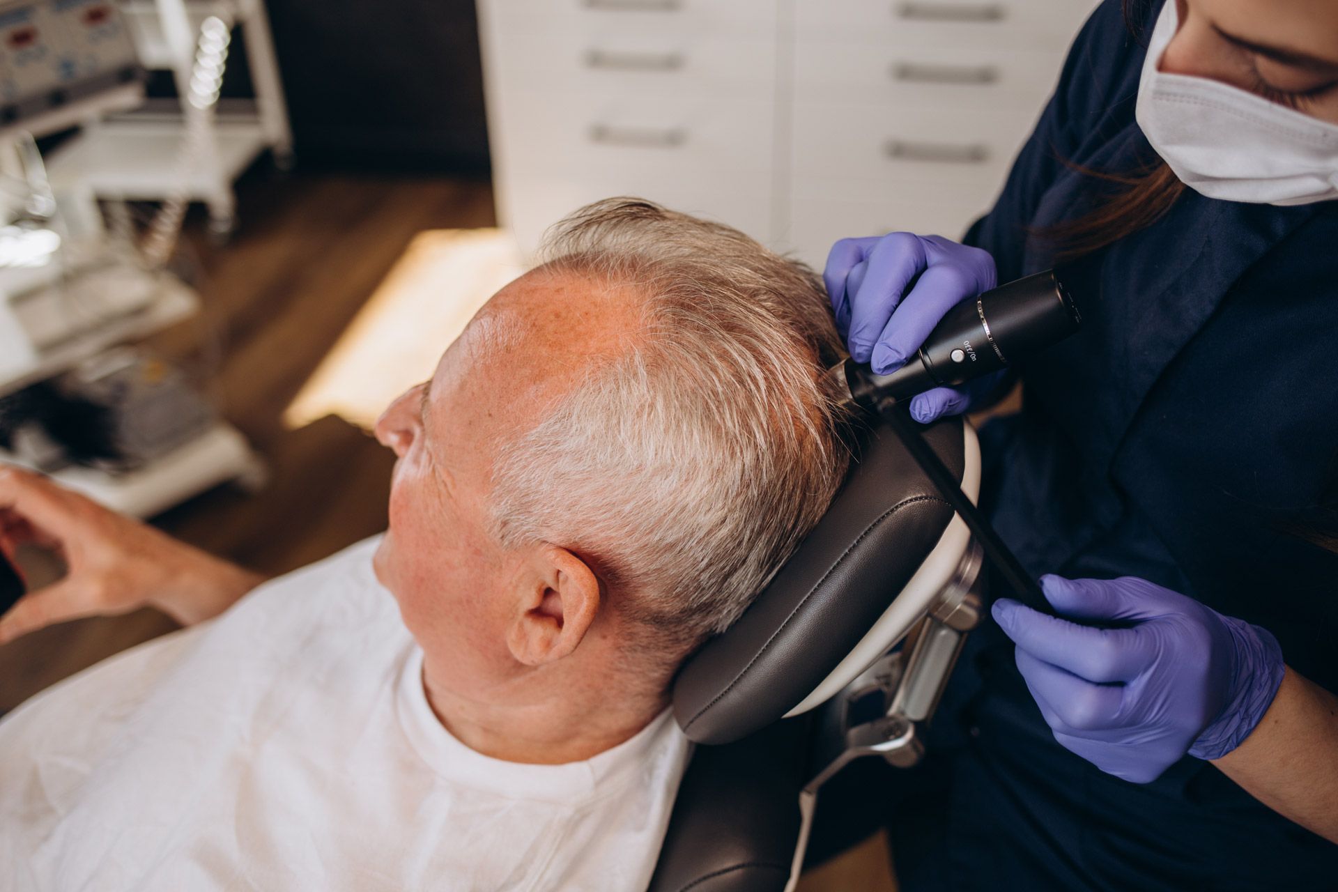 A man is being examined by a specialist for a hair restoration procedure.