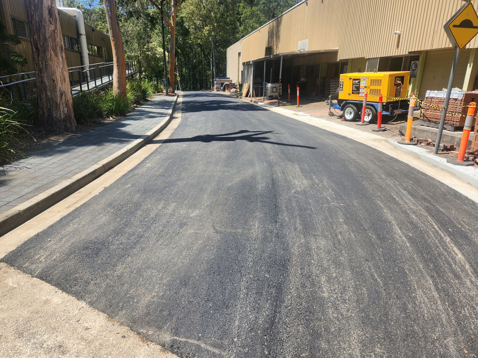 Newly Paved Asphalt Road With Curb on Either Side And Yellow Generator — TAC Asphalt Services in Raymond Terrace, NSW