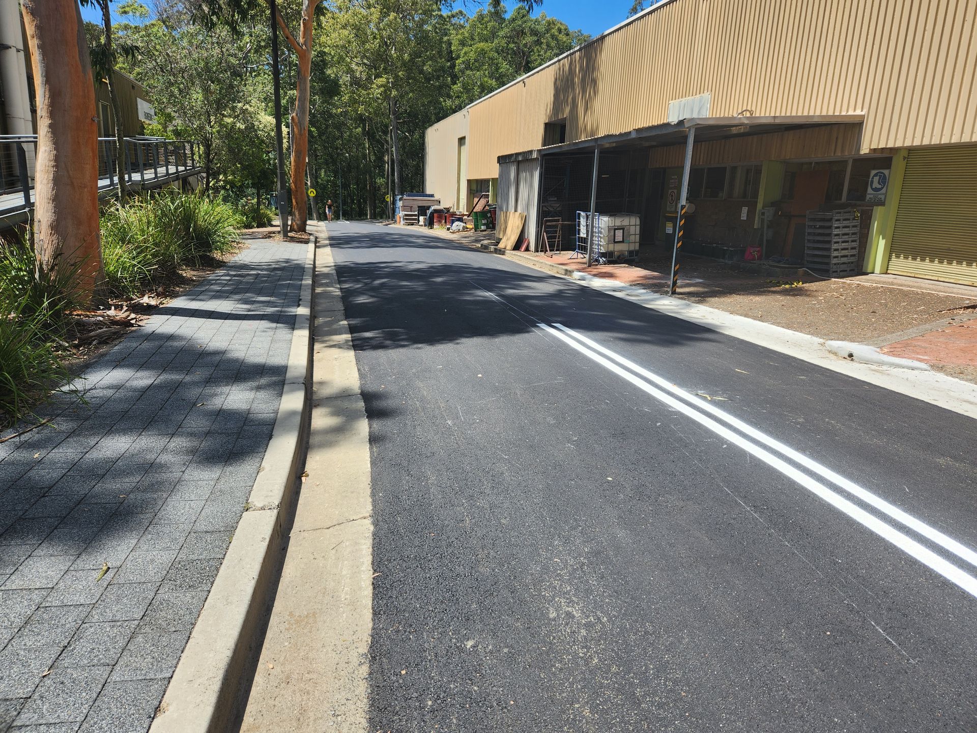 Paved Road With White Lines, a Sidewalk, and a Building Under a Sunny Sky — TAC Asphalt Services in Warners Bay, NSW