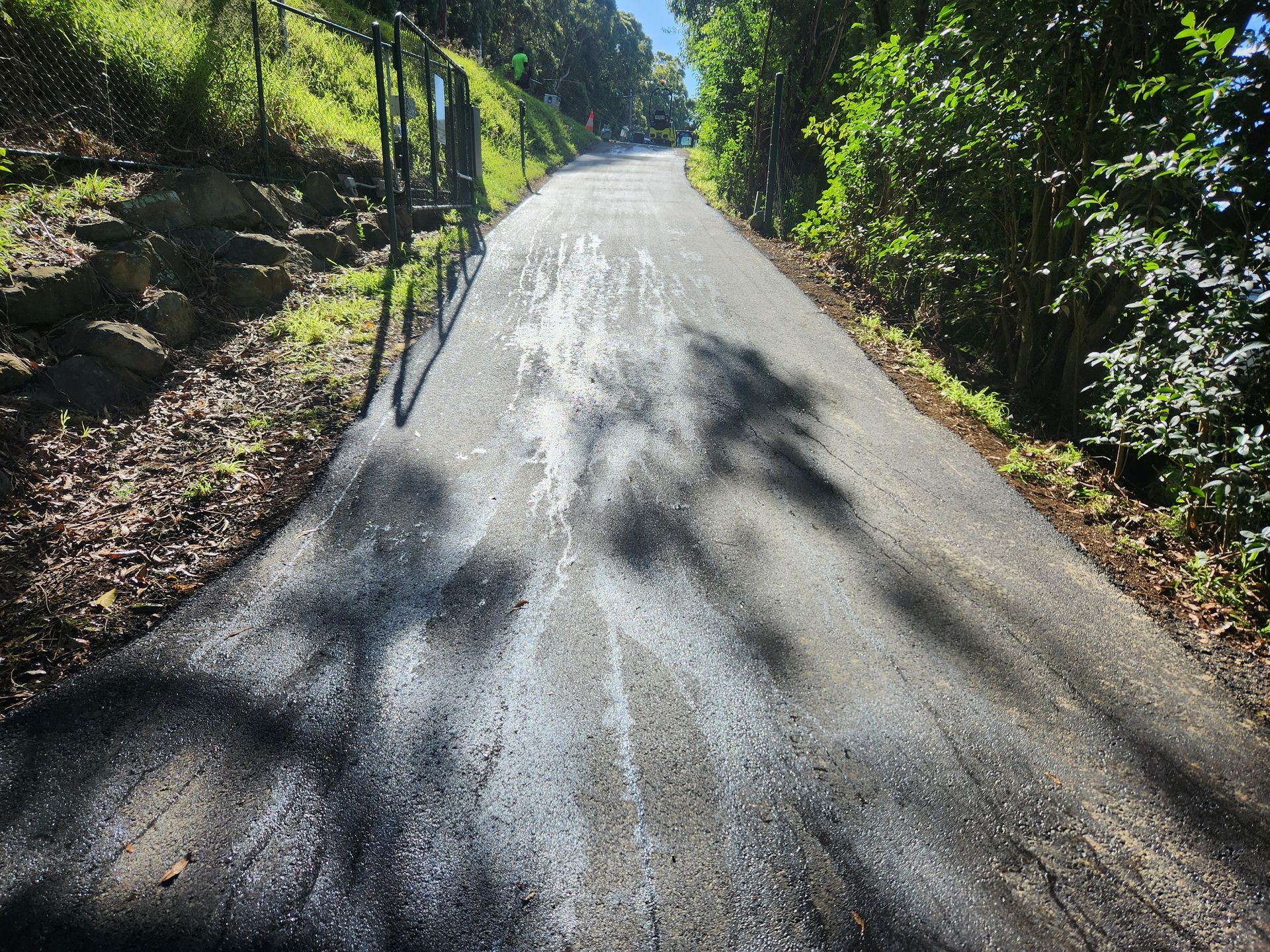 Asphalt Road Leading Uphill, Dappled With White Patches — TAC Asphalt Services in Warners Bay, NSW