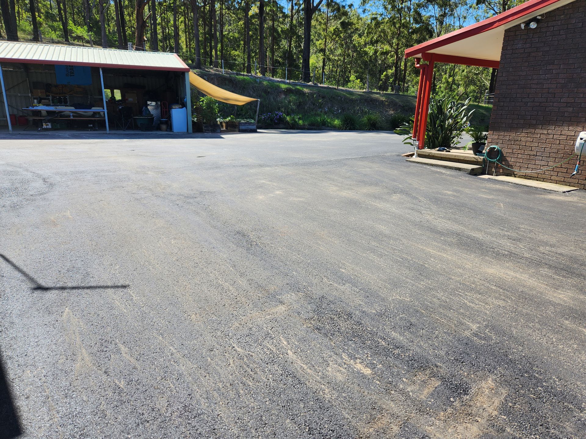 Gravel Driveway With a Shed and Building. Trees in the Background. Sunny Day — TAC Asphalt Services in Central Coast, NSW
