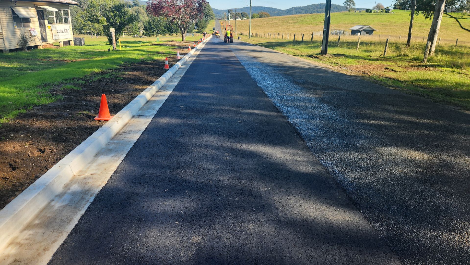 Newly Paved Road With A Concrete Curb And Orange Traffic Cones — TAC Asphalt Services in Warners Bay, NSW