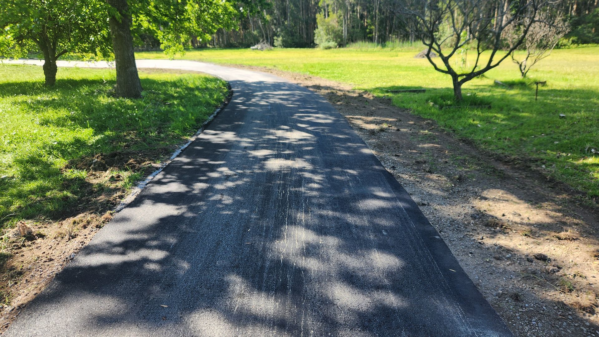 Asphalt Driveway Curves Through A Grassy Area — TAC Asphalt Services in Warners Bay, NSW