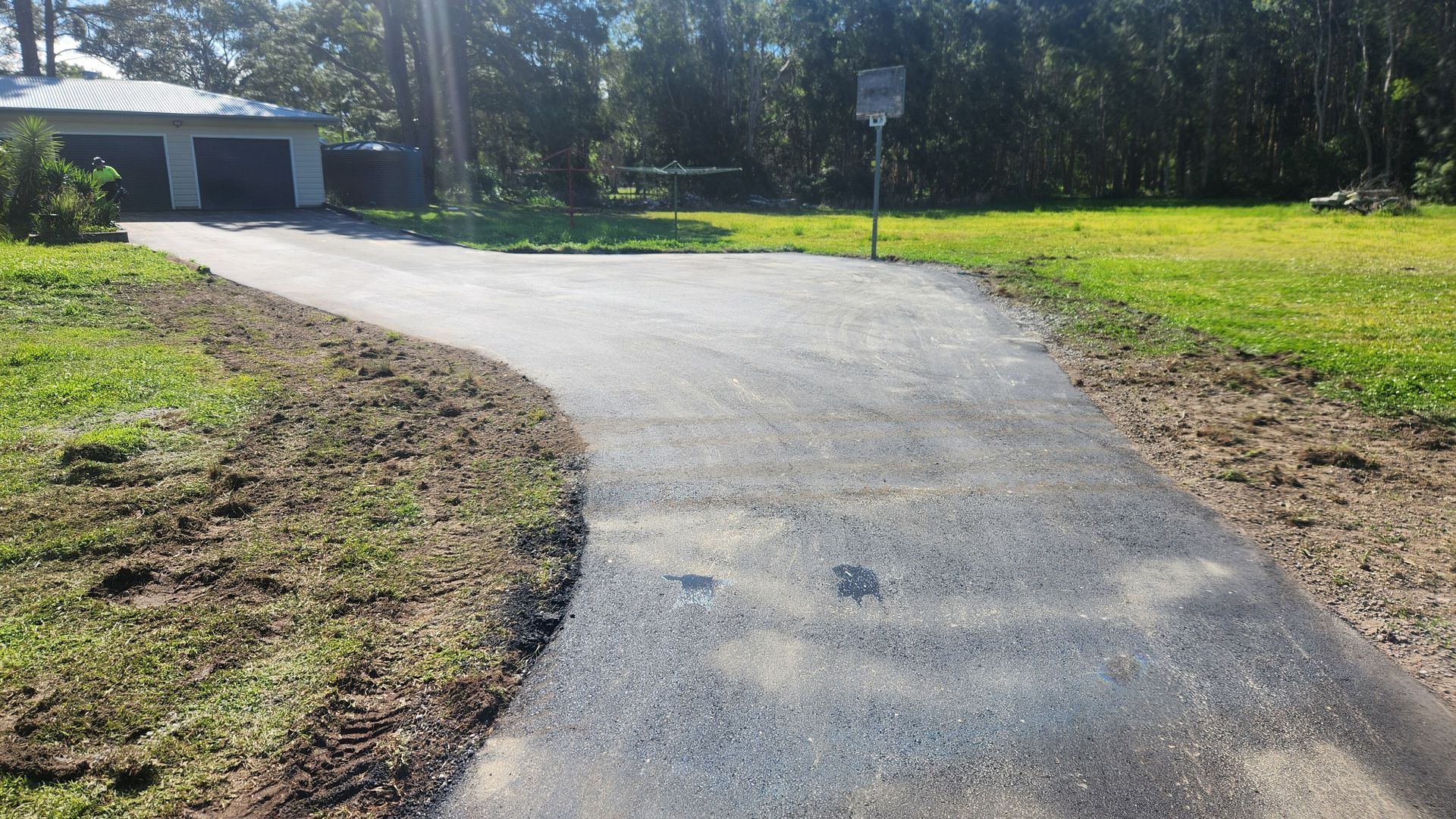 Asphalt Driveway Curves Toward A Garage — TAC Asphalt Services in Warners Bay, NSW