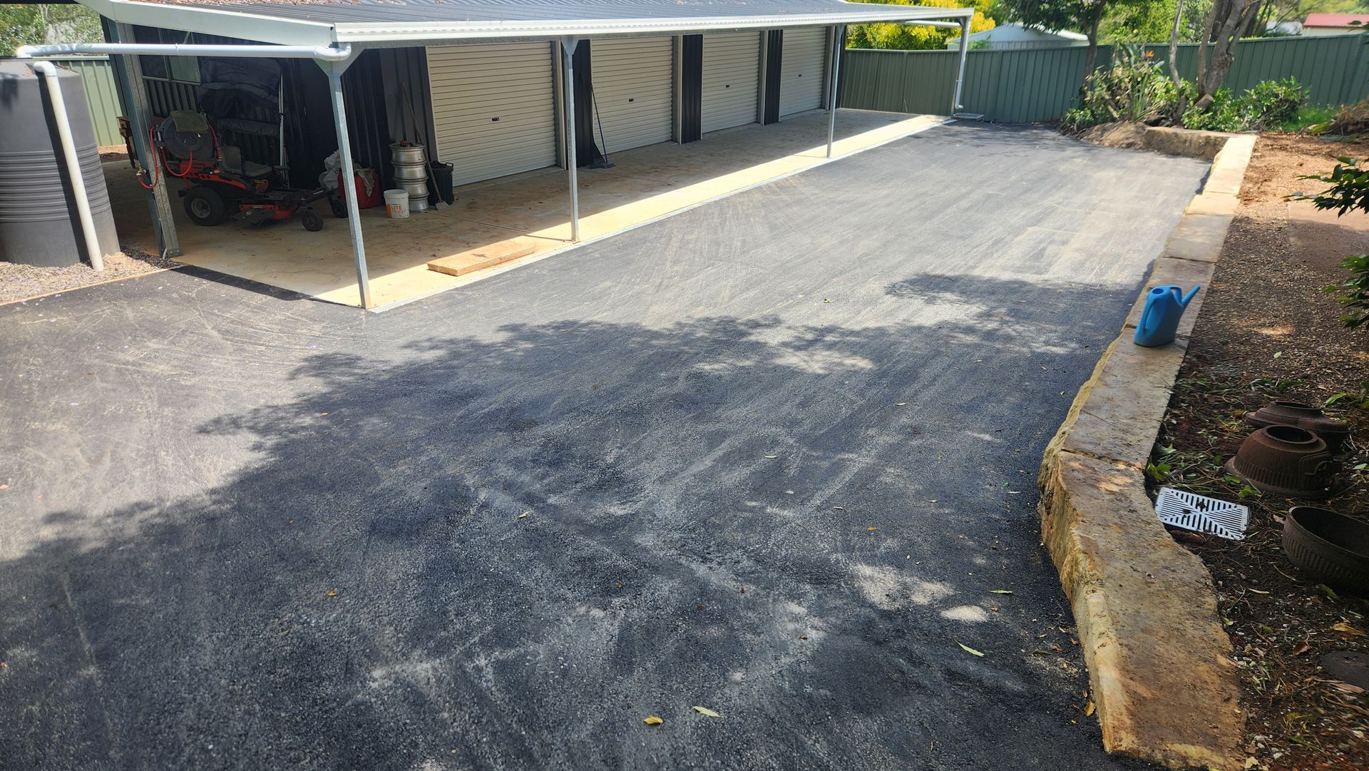 Gravel Driveway Under a Carport With a Water Tank on the Left — TAC Asphalt Services in Warners Bay, NSW