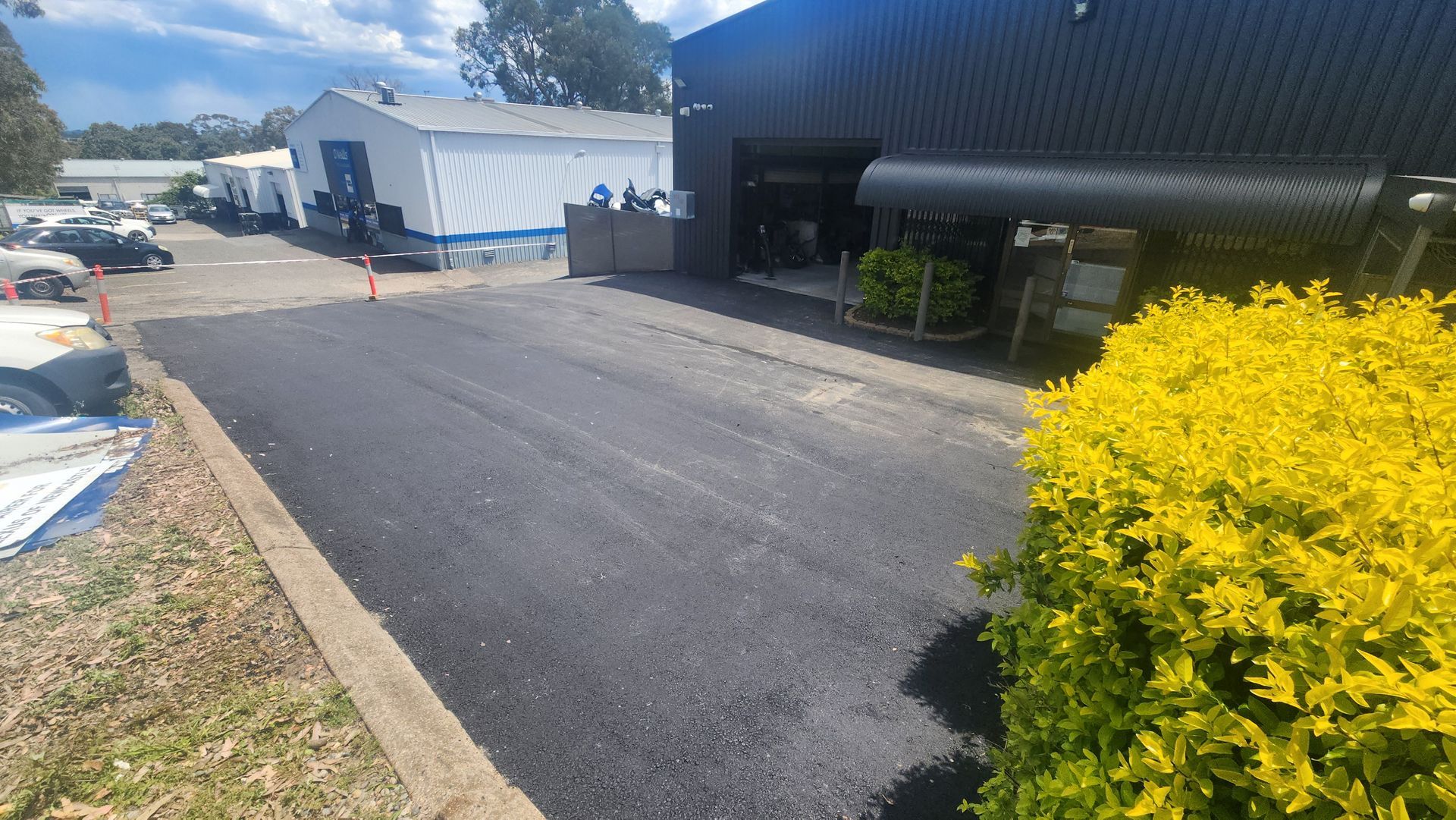 Newly Paved Asphalt Driveway Leading Toward A Dark Building — TAC Asphalt Services in Warners Bay, NSW