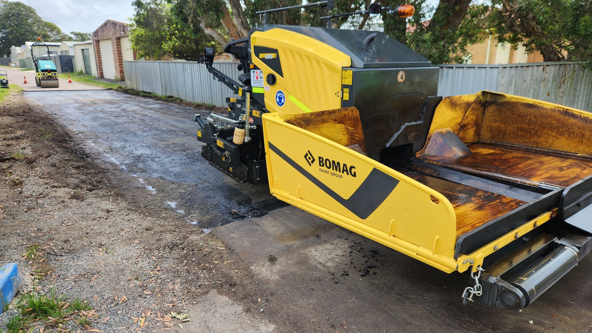 Yellow Asphalt Paver Laying Asphalt On A Road — TAC Asphalt Services in Warners Bay, NSW