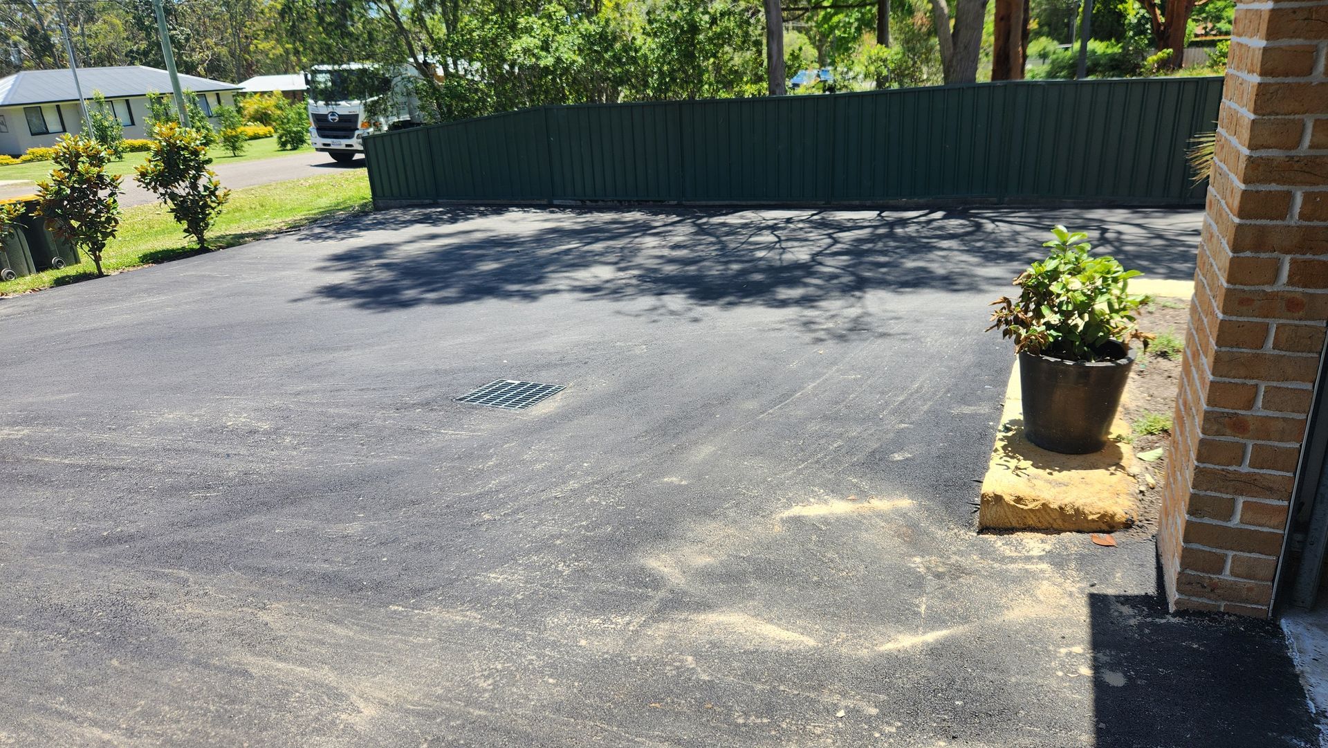 Asphalt Driveway With Green Fence, Trees, and Potted Plant — TAC Asphalt Services in Mid North Coast, NSW