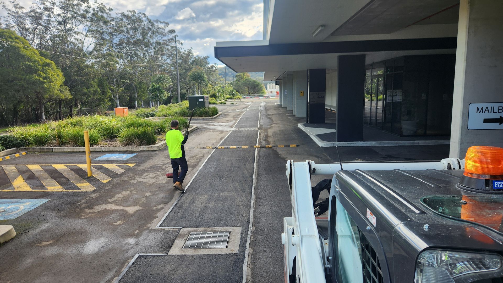 Person In Safety Vest Walks Toward Building Entrance Along Newly Paved Walkway — TAC Asphalt Services in Warners Bay, NSW