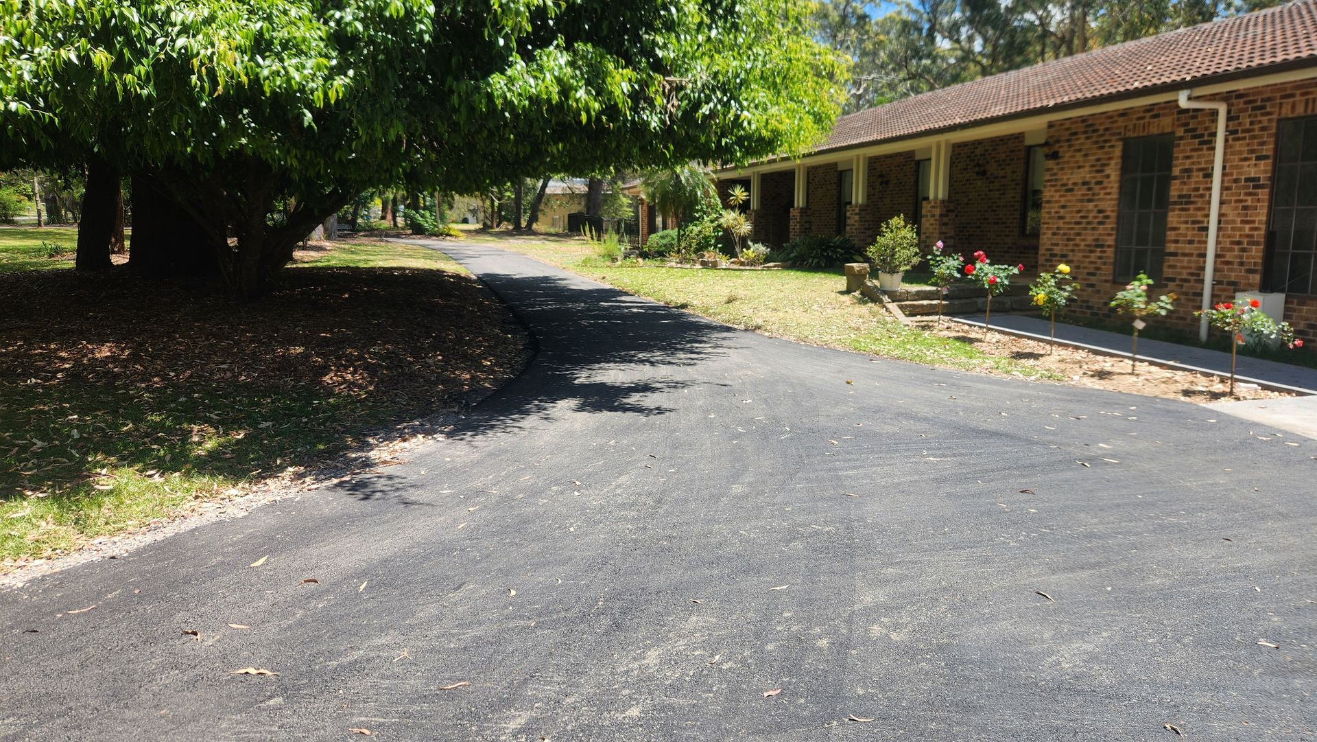 Asphalt Driveway Leading To A Brick House With A Covered Porch — TAC Asphalt Services in Warners Bay, NSW