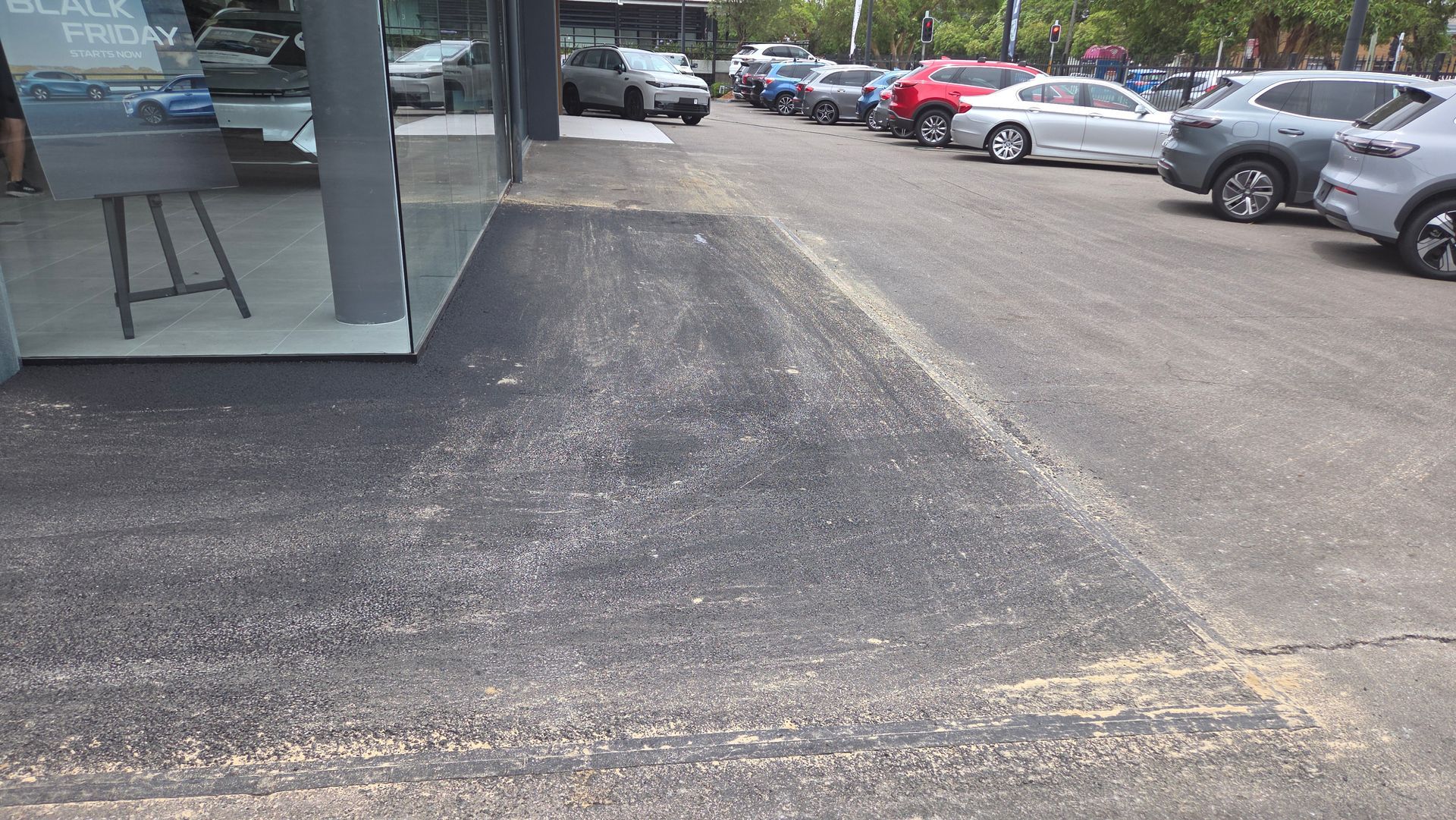 Paved Area in Front of a Car Dealership. Cars Are Parked to the Right — TAC Asphalt Services in Warners Bay, NSW