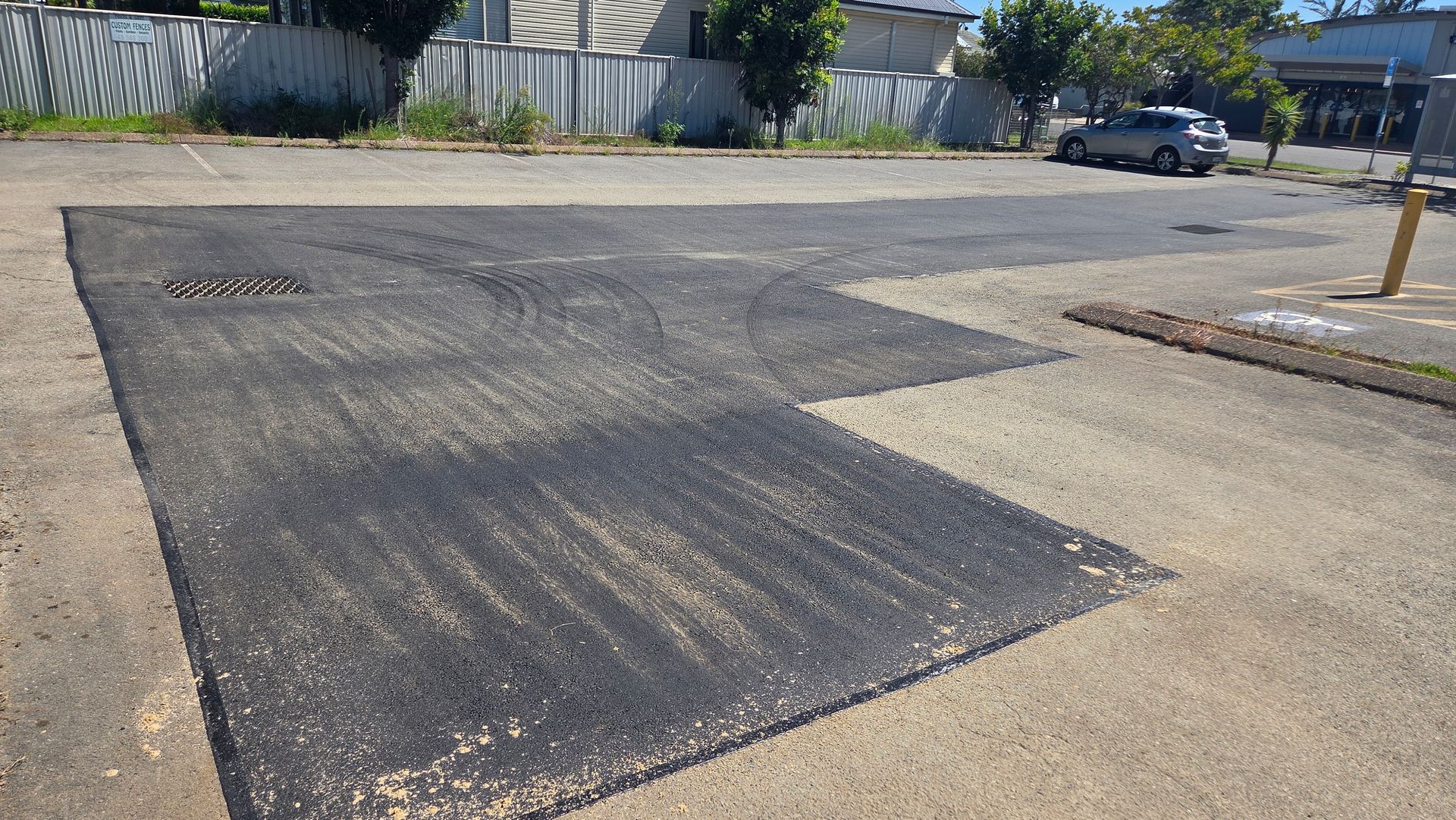 Newly Paved Asphalt Patch On A Gray Road — TAC Asphalt Services in Warners Bay, NSW