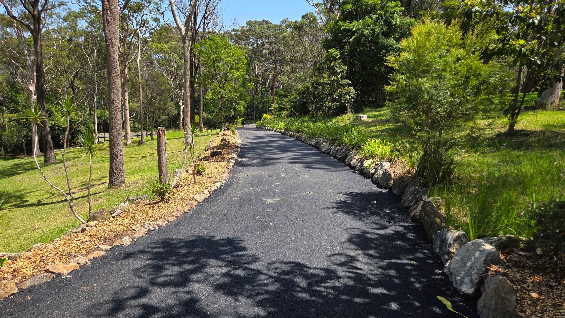 Asphalt Driveway Through A Lush, Green Landscape — TAC Asphalt Services in Warners Bay, NSW