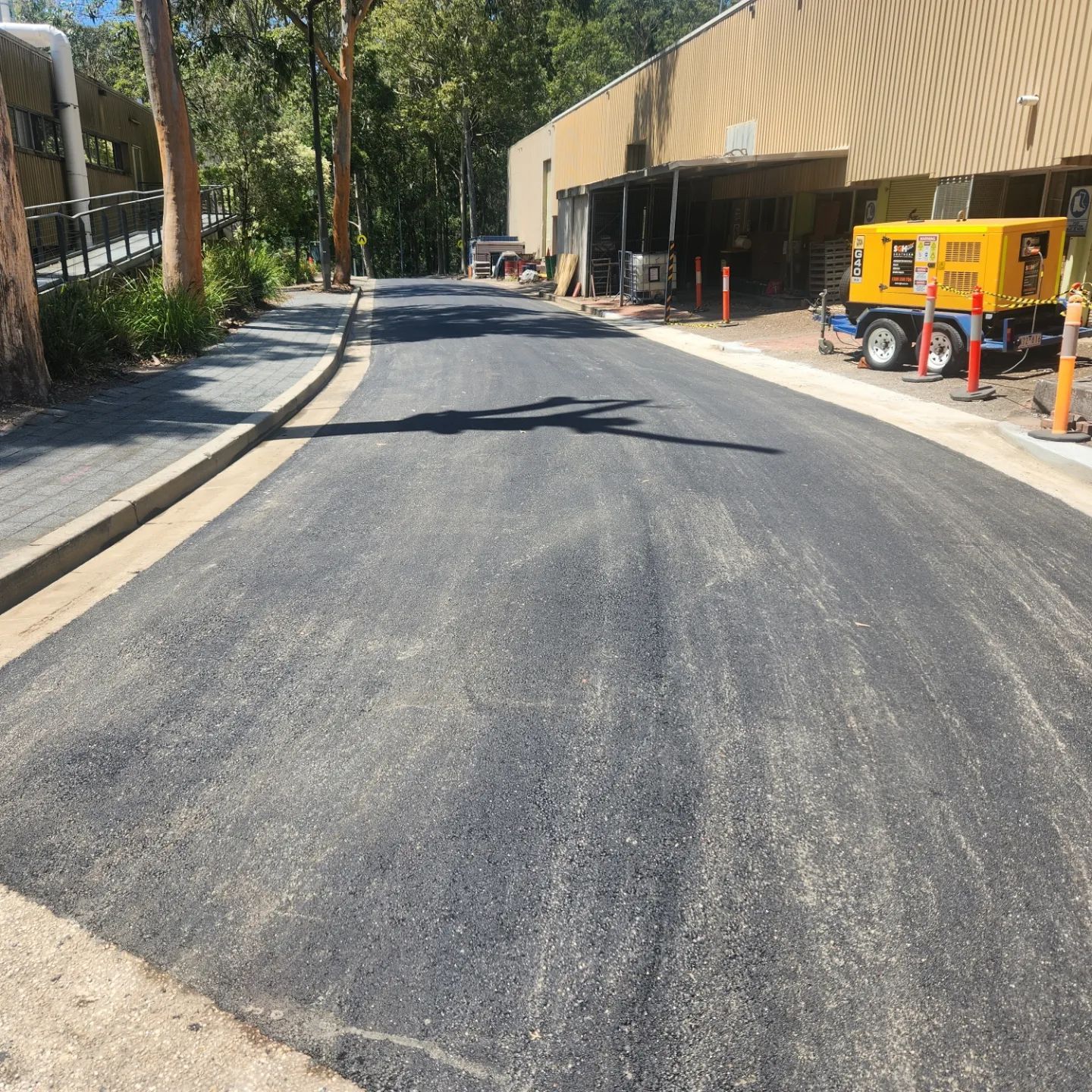 Newly Paved Road With Gray Asphalt And Concrete Edges — TAC Asphalt Services in Warners Bay, NSW