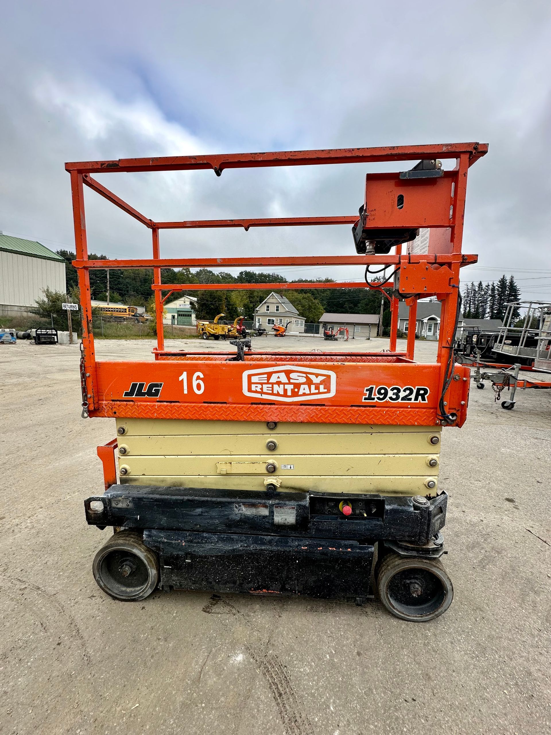 A jlg scissor lift is parked in a dirt lot.