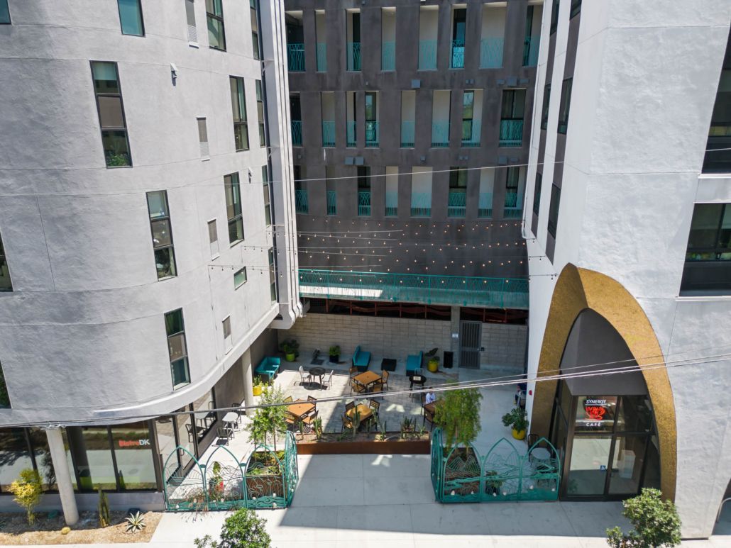 Courtyard between white buildings with a small outdoor dining area and patio umbrellas