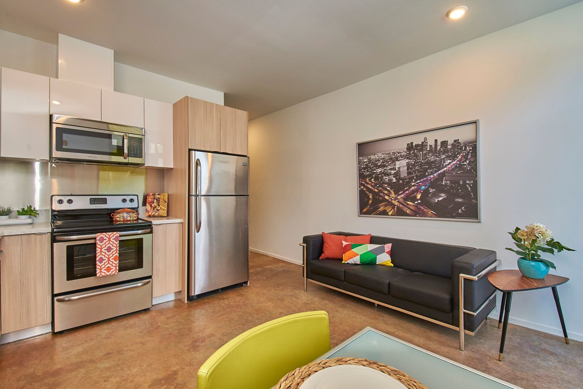 A living room with a couch , table , chairs and a refrigerator.