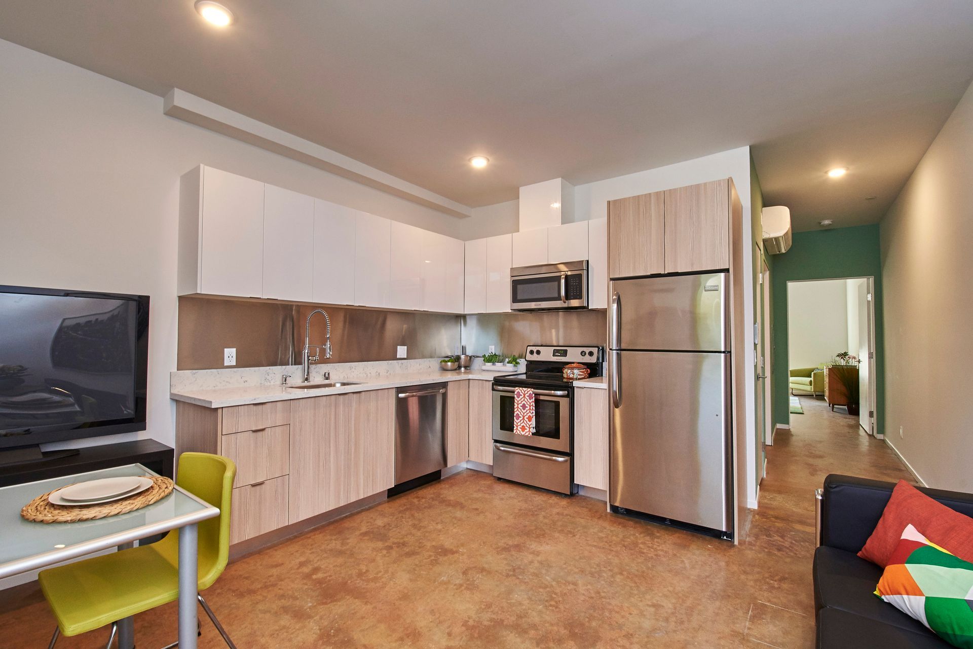 A kitchen with stainless steel appliances and a flat screen tv
