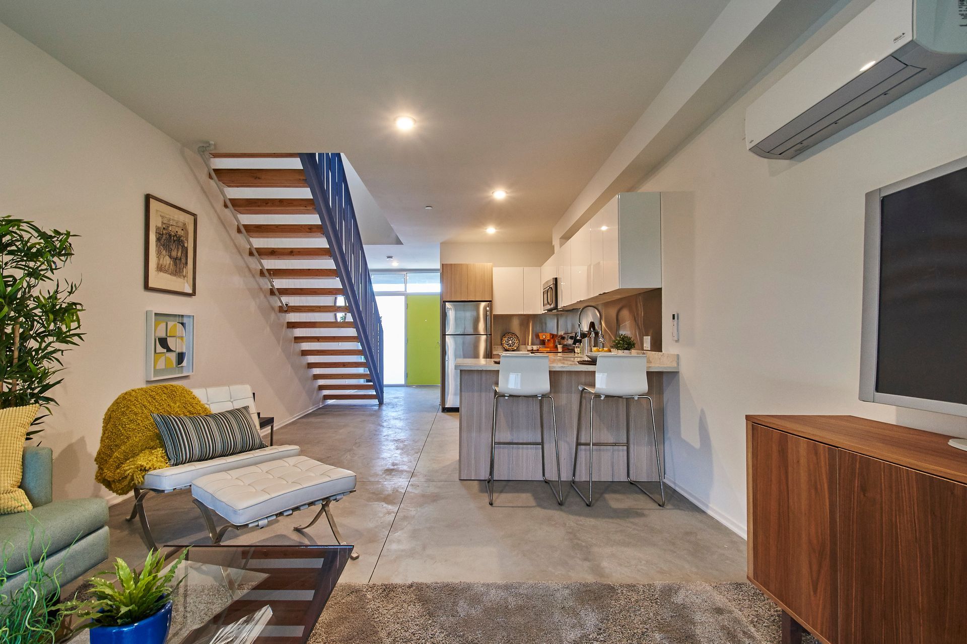 A living room with a staircase leading to the kitchen