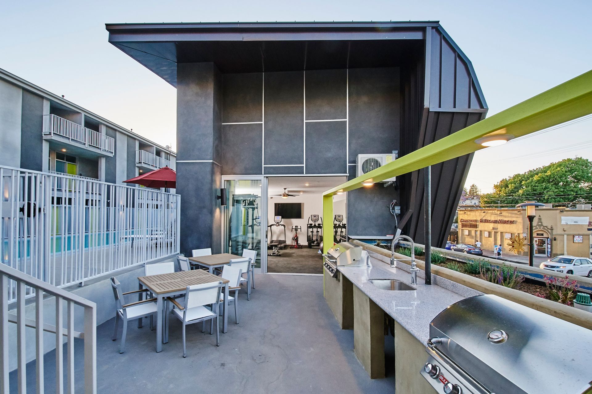 A patio with tables and chairs and a grill in front of a building