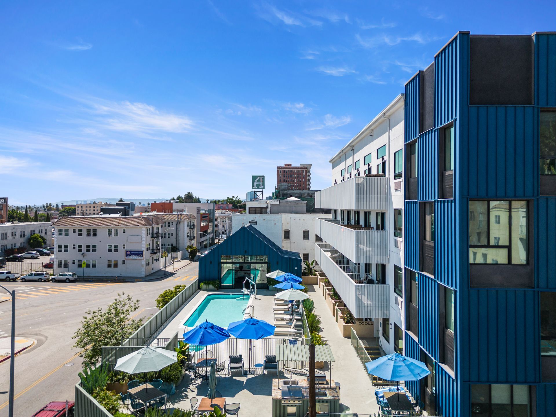 An aerial view of a hotel with a swimming pool and umbrellas.