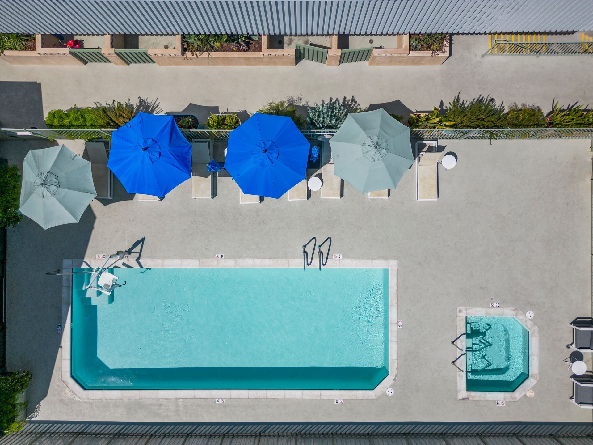 4Mica aerial view of a swimming pool with blue umbrellas