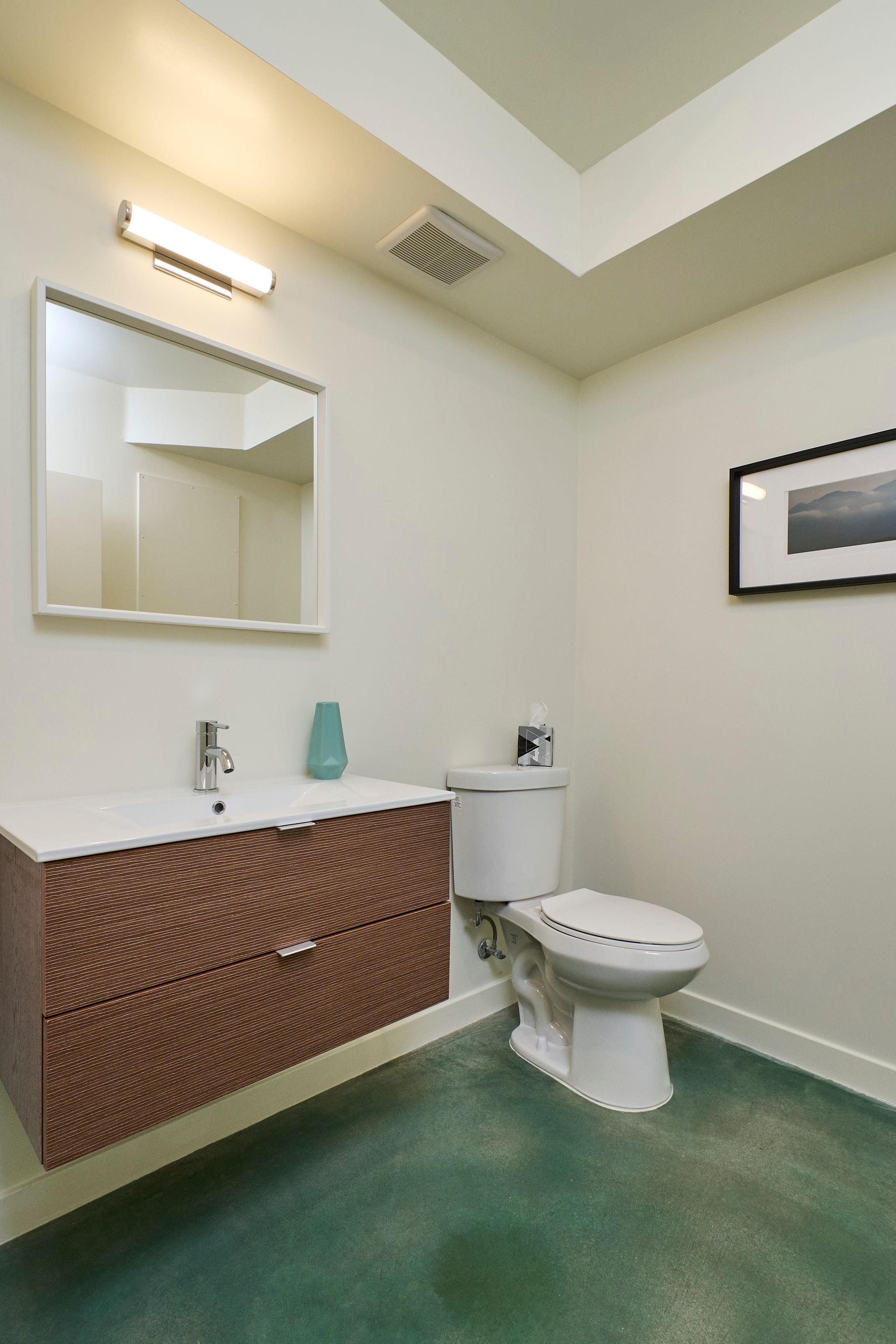 Small bathroom with a sink, mirror, toilet, and green floor