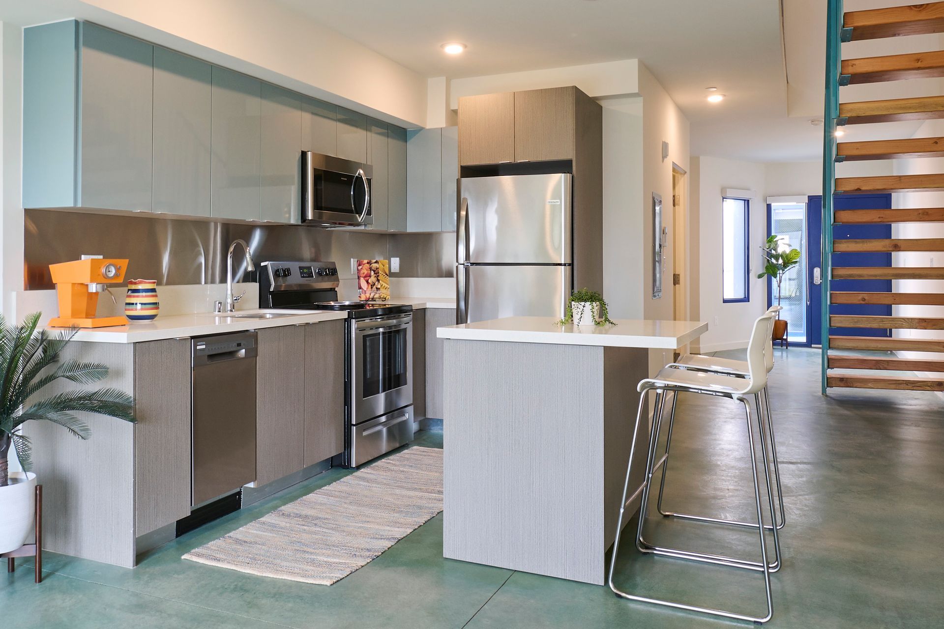 Modern kitchen with stainless steel appliances, island, bar stools, and open dining area