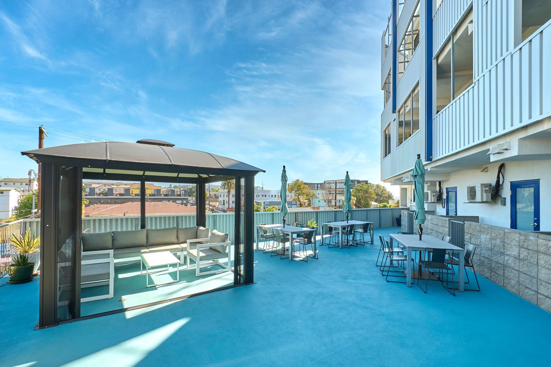 There is a gazebo on the roof of a building with tables and chairs.