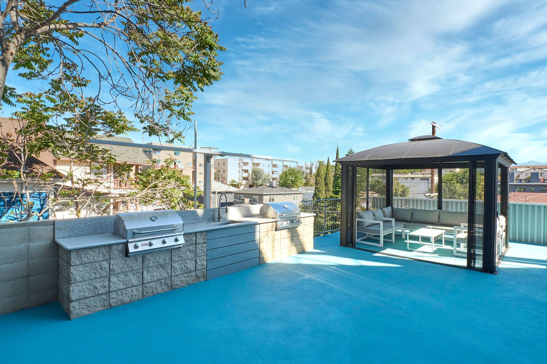 A rooftop patio with a gazebo and a grill