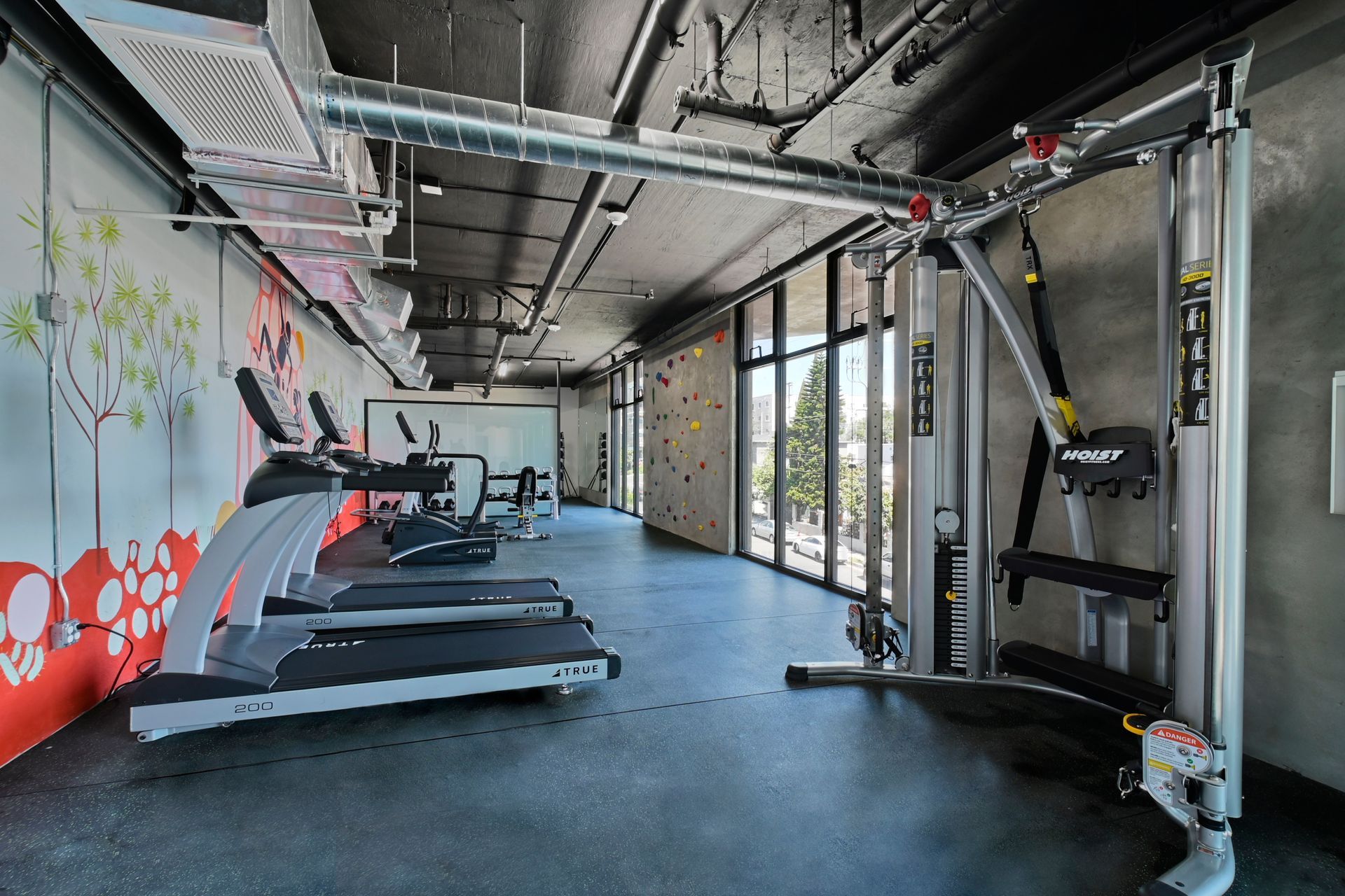 Modern gym interior with treadmills, cable machine, and large windows