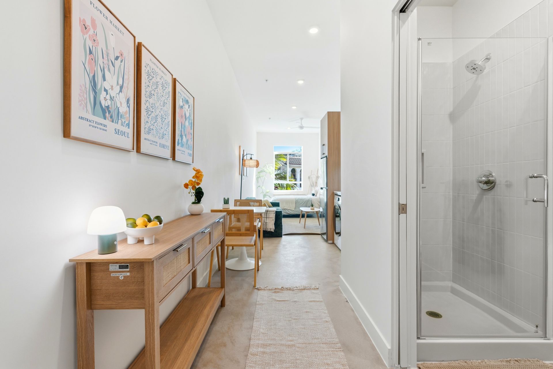 Hallway with console table, art, and shower. Dining area in background.