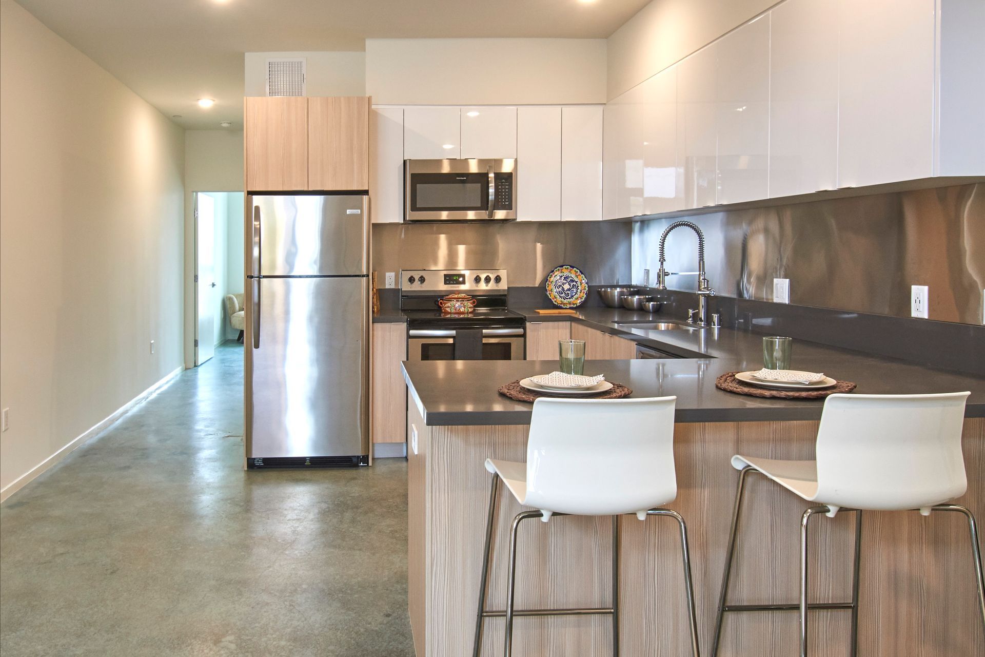 Modern kitchen with stainless steel appliances, wood island, and two white bar stools
