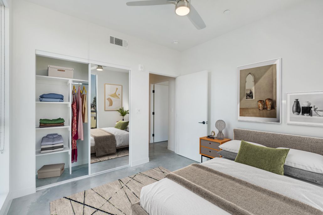 Bright white bedroom with twin beds, open closet, and neutral decor.