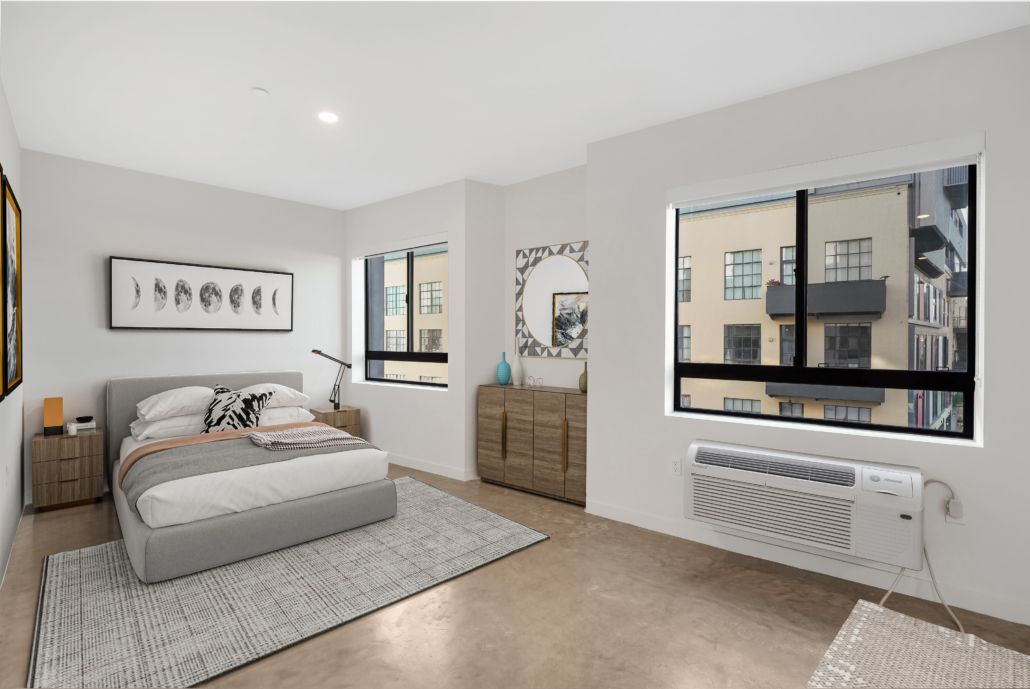 Bright minimalist bedroom with bed, dresser, windows, and radiator