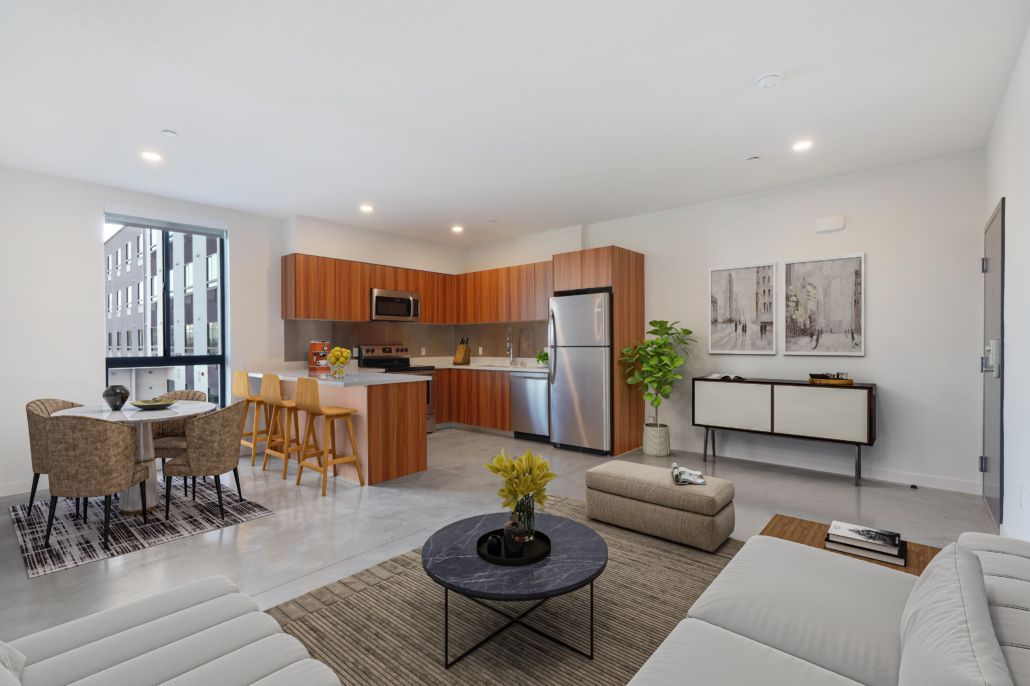 Modern open-plan living room and kitchen with white furniture, wood cabinetry, and stainless steel appliances