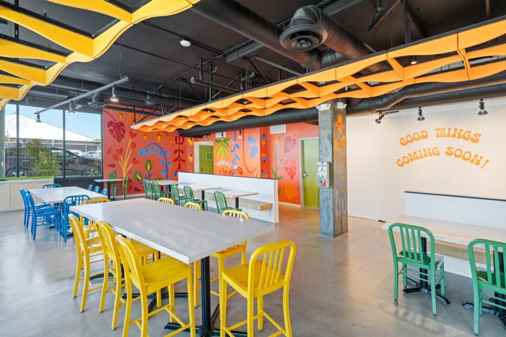 Bright modern café interior with yellow chairs, blue tables, and colorful wall art