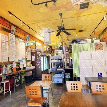 Interior of a cafe with tables, chairs, menu boards, and a counter.