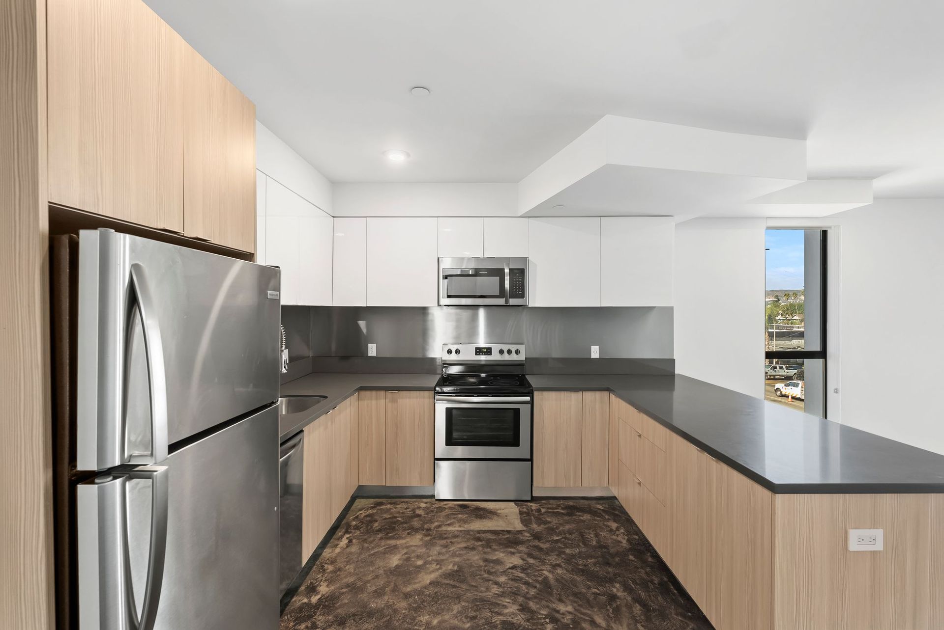 Modern kitchen with stainless steel appliances, white cabinets, and dark countertops