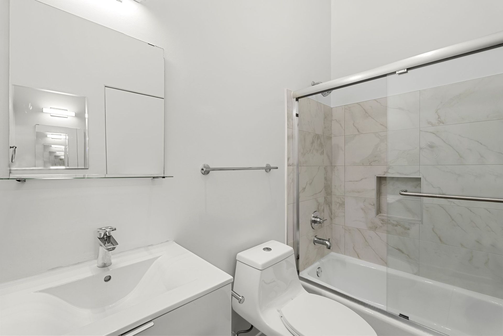 White bathroom with a sink, toilet, and bathtub/shower.
