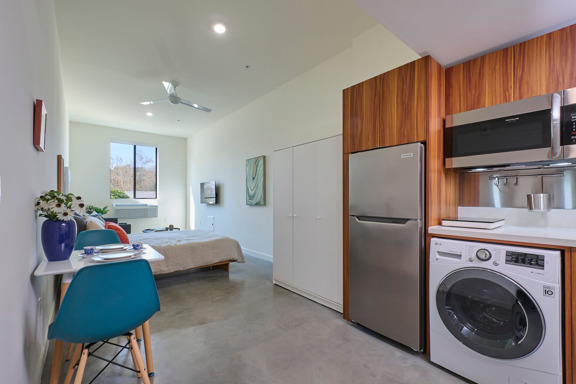 A kitchen with a washing machine , refrigerator , microwave and stove.