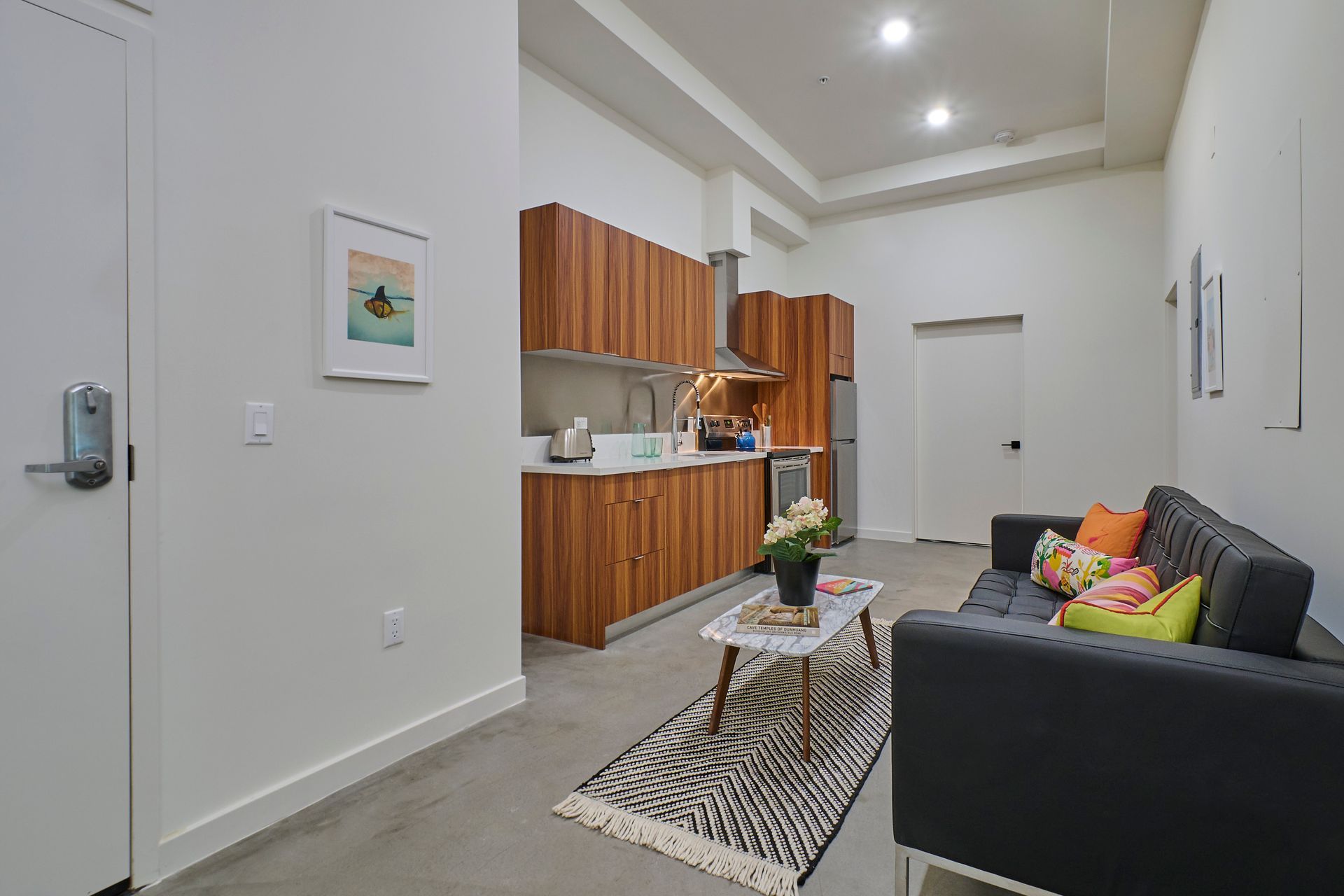 A living room with a couch , coffee table , and kitchen.